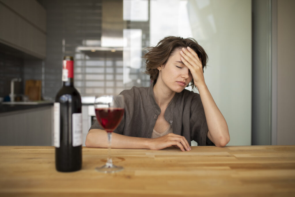 Kobieta zastanawia się, czy objawy uzależnienia od alkoholu dotyczą właśnie jej.